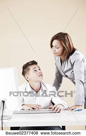 Stock Photo - Woman helping a boy on a computer. Fotosearch