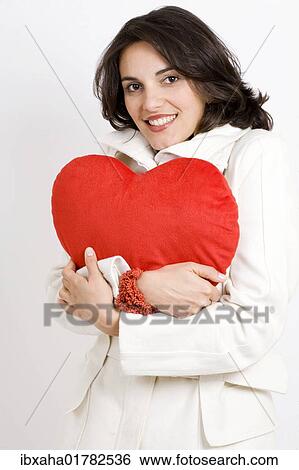 Woman holding a heart-shaped cushion View Large Photo Image Stock Photograph - Woman holding a heart-shaped cushion. Fotosearch