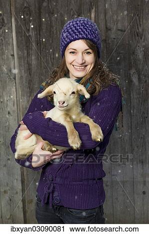 Stock Image - Woman holding a lamb in her arms. Fotosearch