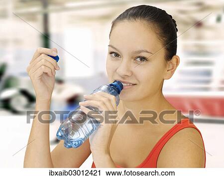 Woman holding a water bottle in a fitness studio View Large Photo Image Stock Image - Woman holding a water bottle in a fitness studio. Fotosearch