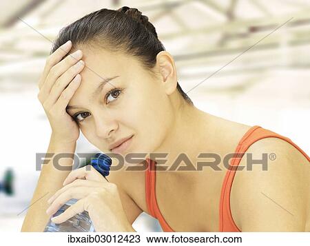 Stock Image - Woman holding a water bottle in a fitness studio. Fotosearch