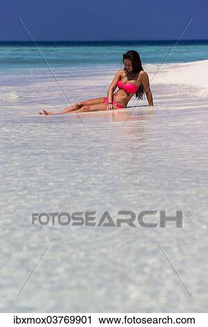Stock Image - "Woman in a pink bikini lying on the beach, Male, North Male Atoll, Maldives, Asia". Fotosearch