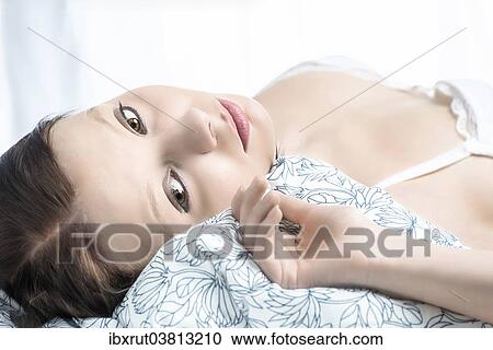 Stock Image - Woman lying in bed. Fotosearch