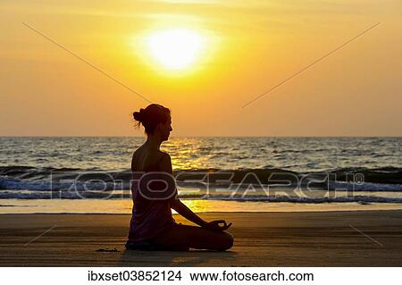 Picture - "Woman meditating on a beach at sunset, Kerala, India, Asia". Fotosearch