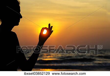 Stock Photo - "Woman meditating on a beach at sunset, Kerala, India, Asia". Fotosearch