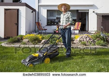 Stock Image - Woman mowing the lawn. Fotosearch