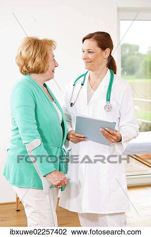 Woman on crutches having a discussion with her doctor View Large Photo Image Stock Image - Woman on crutches having a discussion with her doctor. Fotosearch