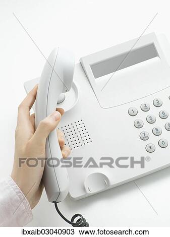 Stock Image - Woman picking up the handset of a telphone. Fotosearch