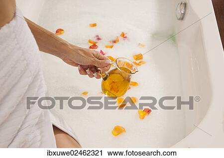 Woman pouring bath oil in a bathtub View Large Photo Image Stock Image - Woman pouring bath oil in a bathtub. Fotosearch