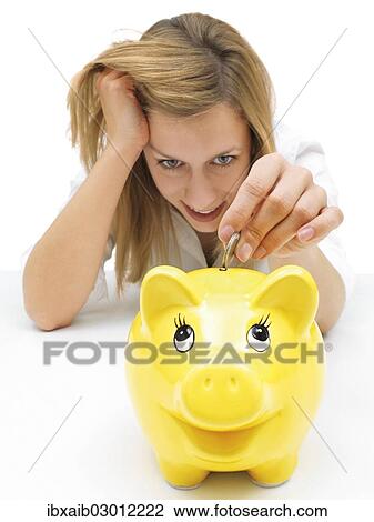 Woman putting a coin into a piggy bank View Large Photo Image Stock Image - Woman putting a coin into a piggy bank. Fotosearch