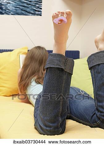 Woman reading with a pacifier hanging from her toe View Large Photo Image Picture - Woman reading with a pacifier hanging from her toe. Fotosearch
