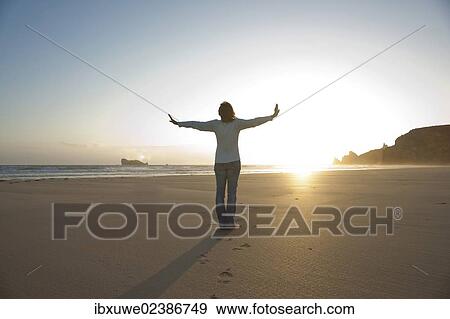 Woman relaxing with her arms outstretched on the beach in the evening View Large Photo Image Stock Photo - Woman relaxing with her arms outstretched on the beach in the evening. Fotosearch