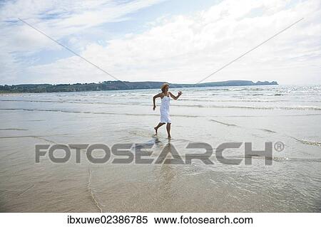 Woman running through small waves on a beach View Large Photo Image Stock Photography - Woman running through small waves on a beach. Fotosearch
