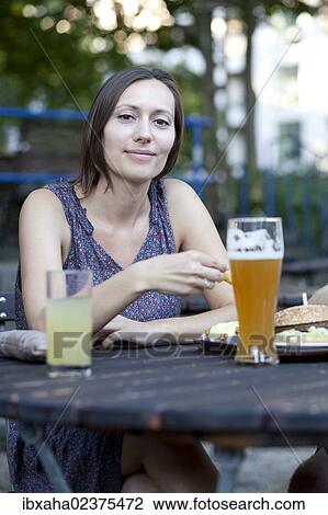Woman sitting in a beer garden View Large Photo Image Stock Image - Woman sitting in a beer garden. Fotosearch