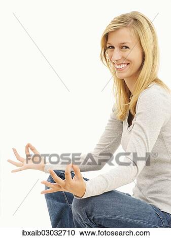 Stock Image - Woman smiling while meditating in a cross-legged position. Fotosearch