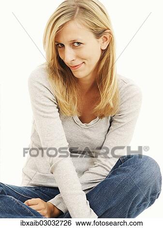 Stock Photograph - Woman smiling while sitting in a cross-legged position. Fotosearch