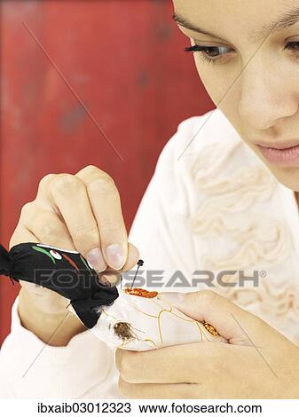 Woman sticking needles into a voodoo doll View Large Photo Image Stock Image - Woman sticking needles into a voodoo doll. Fotosearch
