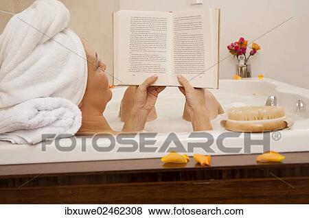 Stock Photo - Woman taking a bath and reading a book. Fotosearch