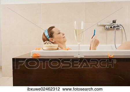Woman using a mobile phone in the bathtub View Large Photo Image Stock Image - Woman using a mobile phone in the bathtub. Fotosearch