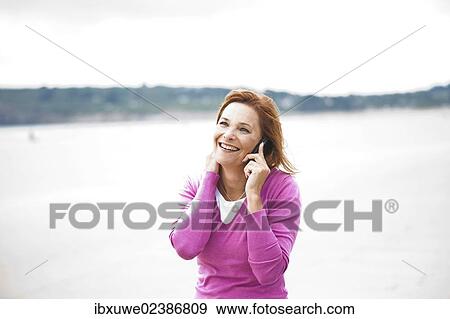 Woman using a mobile phone on a beach View Large Photo Image Stock Photo - Woman using a mobile phone on a beach. Fotosearch