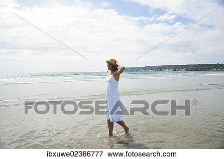 Woman walking through small waves on a beach View Large Photo Image Stock Photo - Woman walking through small waves on a beach. Fotosearch