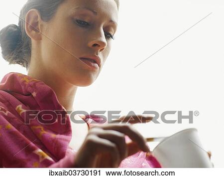 Stock Image - Woman wearing a bathrobe smoking a cigarette. Fotosearch