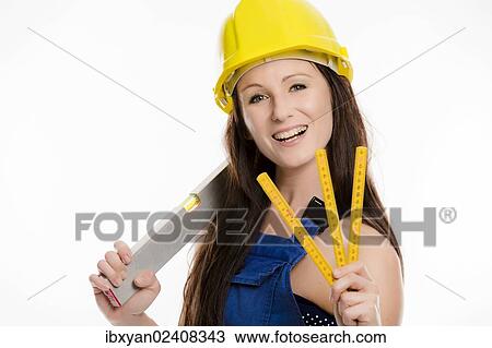 Woman wearing blue overalls and a hardhat holding a folding carpenter's ruler and a spirit level View Large Photo Image Stock Image - Woman wearing blue overalls and a hardhat holding a folding carpenter's ruler and a spirit level. Fotosearch
