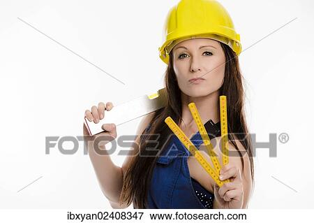 Woman wearing blue overalls and a hardhat holding a folding carpenter's ruler and a spirit level View Large Photo Image Stock Photo - Woman wearing blue overalls and a hardhat holding a folding carpenter's ruler and a spirit level. Fotosearch