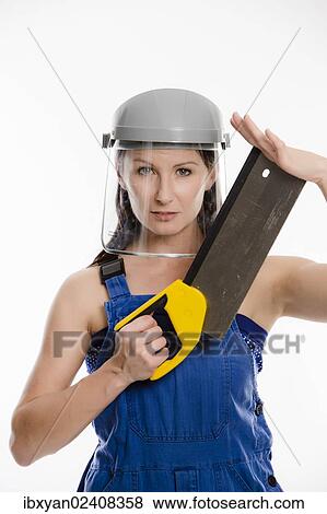 Woman wearing blue overalls and a protective helmet holding a saw View Large Photo Image Stock Photo - Woman wearing blue overalls and a protective helmet holding a saw. Fotosearch