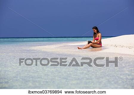 "Woman with a book sitting on the beach, Male, North Male Atoll, Maldives, Asia" View Large Photo Image Picture - "Woman with a book sitting on the beach, Male, North Male Atoll, Maldives, Asia". Fotosearch
