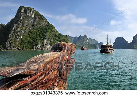Stock Photography - "Wood carving, dragon head at the bow on a junk, Halong Bay, karst cone in the back, Vietnam, Southeast Asia, Asia". Fotosearch