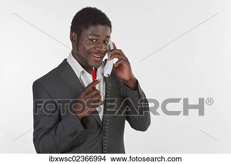 "Young black man in a suit making a phone call in an office, smiling" View Large Photo Image Picture - "Young black man in a suit making a phone call in an office, smiling". Fotosearch