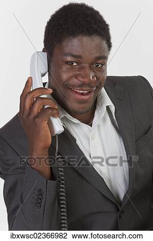 "Young black man in a suit making a phone call in an office, smiling" View Large Photo Image Stock Image - "Young black man in a suit making a phone call in an office, smiling". Fotosearch