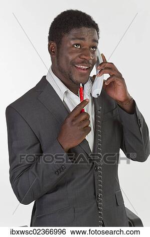 "Young black man in a suit making a phone call in an office, looking pensively" View Large Photo Image Stock Photograph - "Young black man in a suit making a phone call in an office, looking pensively". Fotosearch