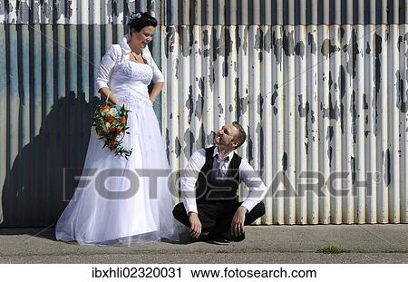 Young bridal couple posing in front of a wall of corrugated iron View Large Photo Image Stock Image - Young bridal couple posing in front of a wall of corrugated iron. Fotosearch