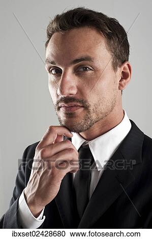 "Young businessman wearing a suit with his hand on his chin, pensive, portrait" View Large Photo Image Stock Image - "Young businessman wearing a suit with his hand on his chin, pensive, portrait". Fotosearch