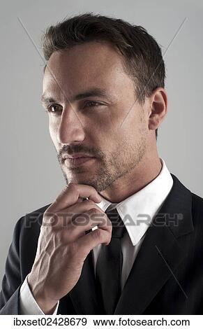 "Young businessman wearing a suit with his hand on his chin, pensive, portrait" View Large Photo Image Stock Photo - "Young businessman wearing a suit with his hand on his chin, pensive, portrait". Fotosearch