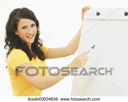 Stock Photograph - Young businesswoman standing next to a flipchart. Fotosearch