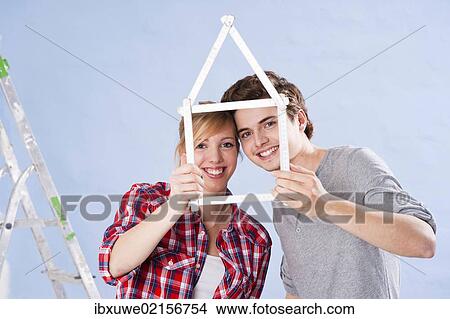 Young couple holding a folding carpenter's ruler in the shape of a house View Large Photo Image Picture - Young couple holding a folding carpenter's ruler in the shape of a house. Fotosearch