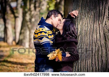 Young couple kissing in a park in autumn View Large Photo Image Stock Photo - Young couple kissing in a park in autumn. Fotosearch