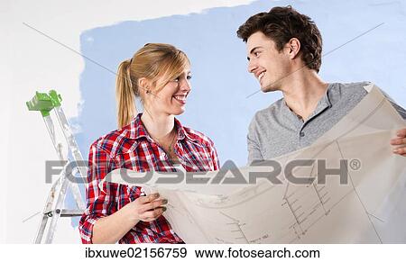 Young couple looking at a plan View Large Photo Image Stock Photo - Young couple looking at a plan. Fotosearch