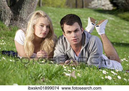 "Young couple lying on a lawn in a park, spring" View Large Photo Image Picture - "Young couple lying on a lawn in a park, spring". Fotosearch