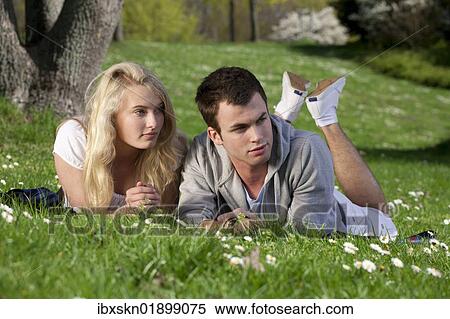 "Young couple lying on a lawn in a park, spring" View Large Photo Image Stock Photography - "Young couple lying on a lawn in a park, spring". Fotosearch
