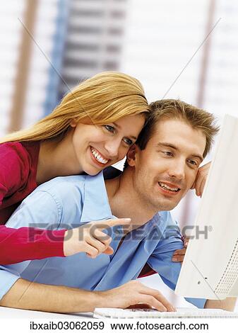 Young couple using a computer View Large Photo Image Stock Photo - Young couple using a computer. Fotosearch