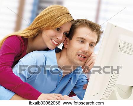 Young couple using a computer View Large Photo Image Stock Photograph - Young couple using a computer. Fotosearch