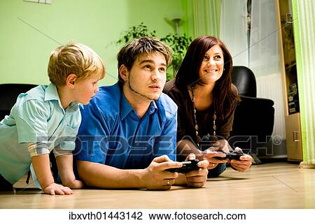 Stock Image - Young family playing with a game console. Fotosearch