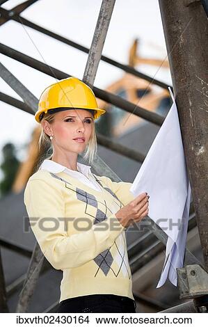 Young female architect with hard hat at a construction site View Large Photo Image Picture - Young female architect with hard hat at a construction site. Fotosearch