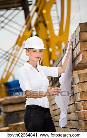 Stock Image - Young female constructor at building site. Fotosearch