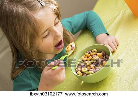 Stock Photo - "young girl eating cornflakes from the bowl, Germany, Europe". Fotosearch
