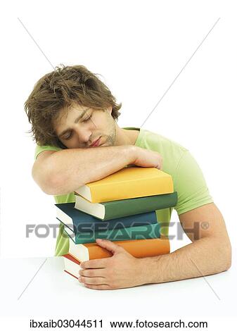 Stock Image - "Young male student with a stack of books, tired, exhausted, asleep". Fotosearch